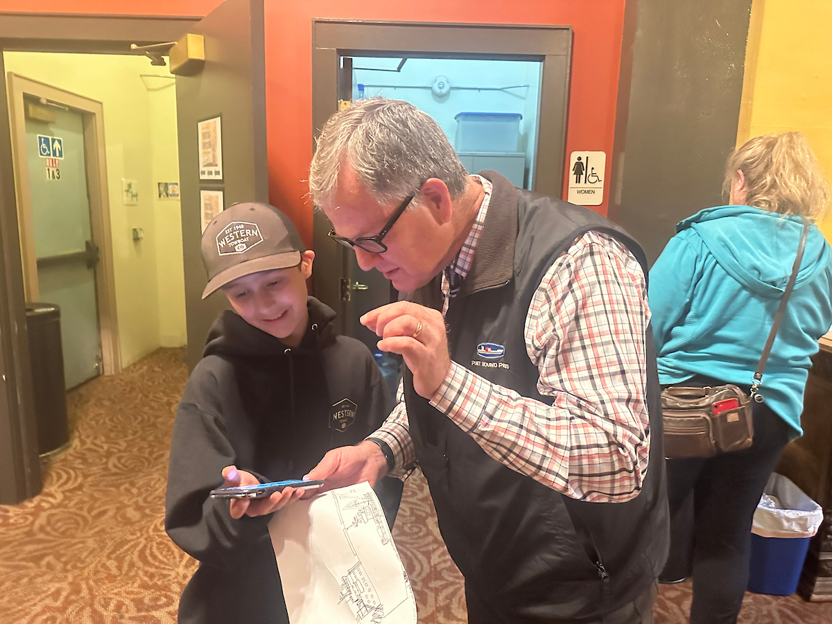 A man and adolescent boy look at information on a phone together. 