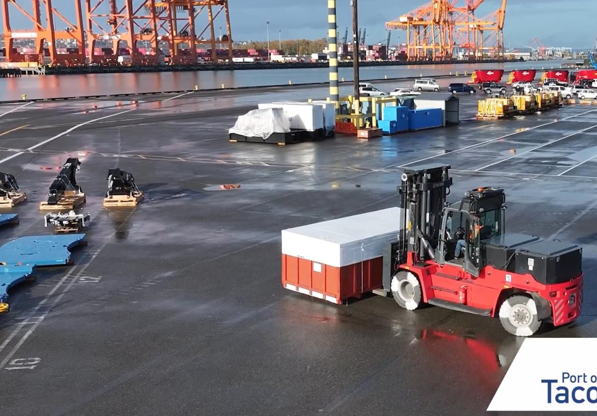 A red forklift moves a container through a port terminal.